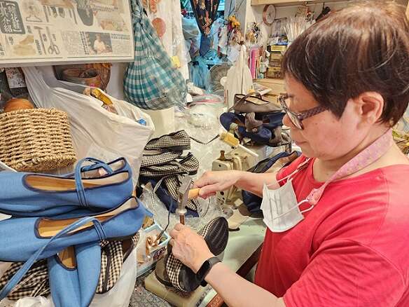 「年繡花鞋」製鞋師傅陳太太為繡花鞋釘上扣環。（鄭佩雯拍攝）