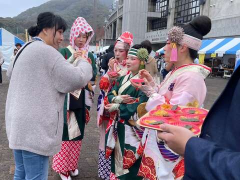 身着传统服饰的表演团体成员於台南观光摊位体验特色试吃活动，透过美食交流加深对台南的认识。