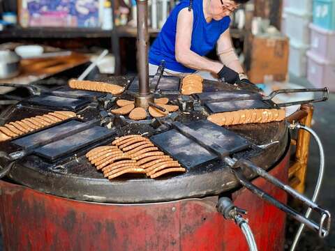 老式煎饼机烤饼的样子，令不少人伫足观赏，图为第三代制饼的情形。（张耘书拍摄）