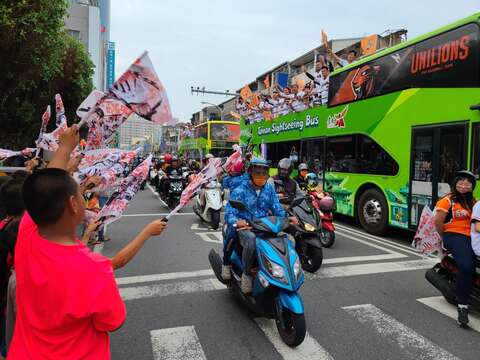 民眾搖隊旗歡迎遊行車隊