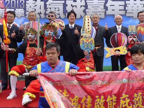 貴賓手持熱氣球板與身心障礙表演團體合影，象徵愛在台南希望起飛